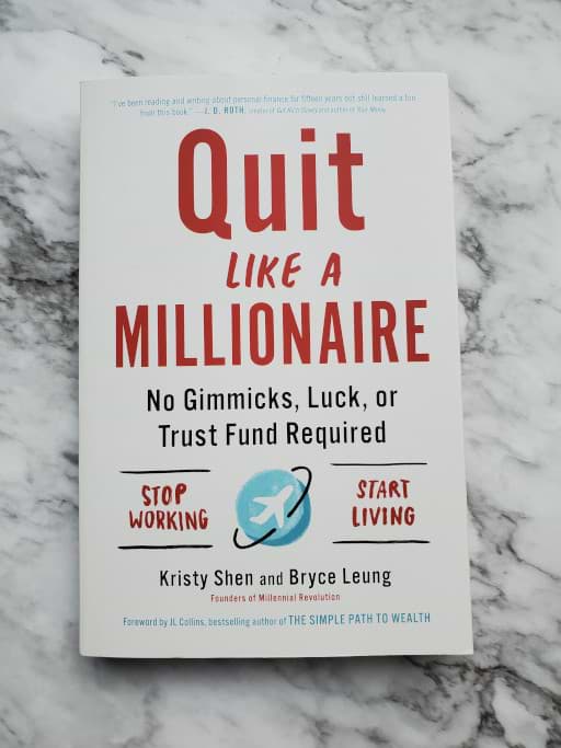 Book on marble background. Quit Like A Millionaire.